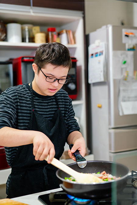 Teenage boy with Down's Syndrome cooking in a domestic kitchen